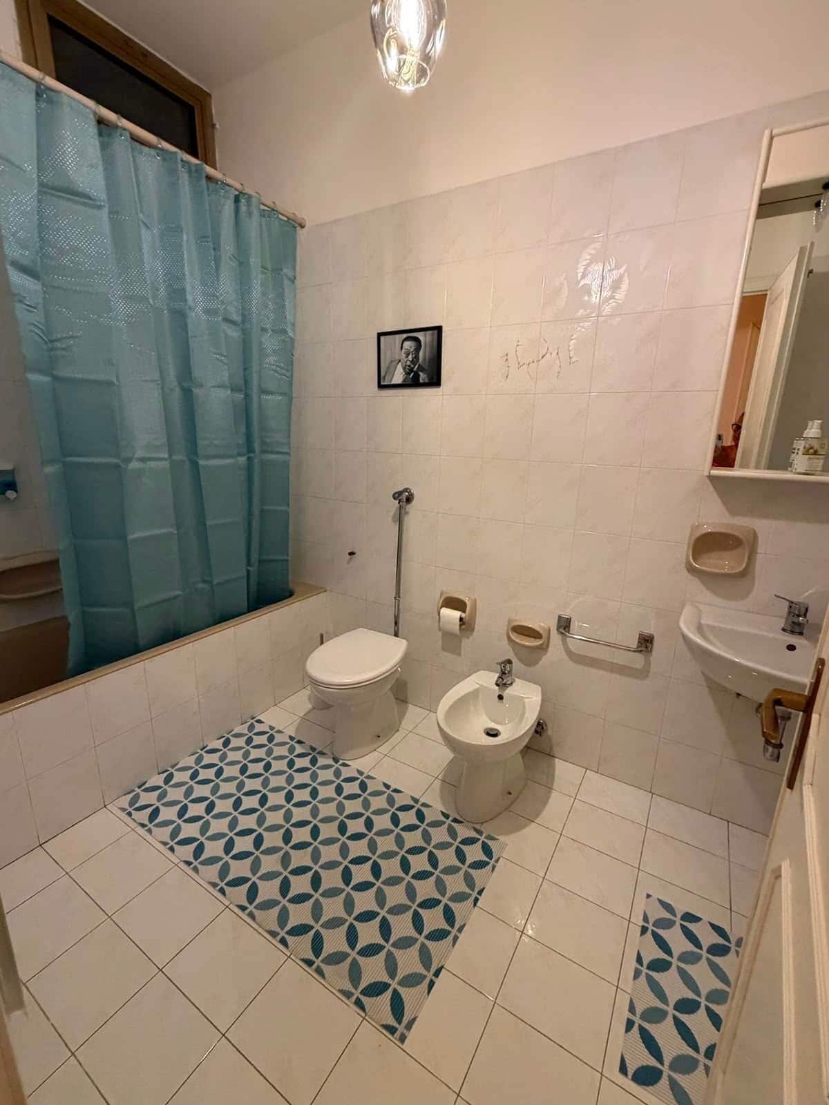 Ein Badezimmer mit Toilette, Bidet, Waschbecken und Duschbereich.