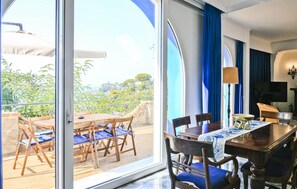 Ein Zimmer mit Esstisch, Stühlen und Blick auf Grünflächen.