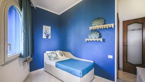 Een slaapkamer met een bed, een raam met gordijnen, een wandplank en een deur.
