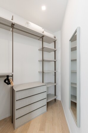 A walk-in closet with open shelving, a built-in wardrobe, and a mirrored closet door. - La Corte Vermena by Wonderful Italy (Bologna)