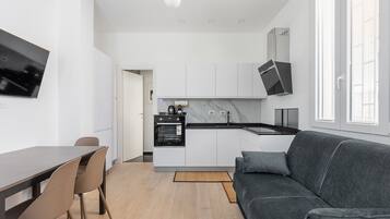 Een moderne keuken met witte kasten, een zwart aanrecht en een inbouwoven.