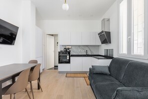 Eine moderne Küche mit weißen Schränken, einer schwarzen Arbeitsplatte und einem eingebauten Backofen.