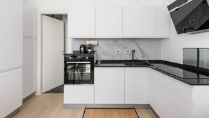 A modern kitchen with white cabinetry, a black countertop, and a built-in oven. - La Corte Vermena by Wonderful Italy (Bologna)