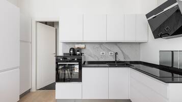 Een moderne keuken met witte kasten, een zwart aanrecht en een ingebouwde oven.