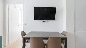 Ein stilvoller Essbereich mit Wand-Fernseher, einem rechteckigen Tisch und vier Stühlen.