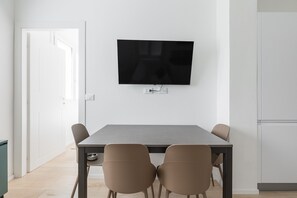 Ein stilvoller Essbereich mit Wand-Fernseher, einem rechteckigen Tisch und vier Stühlen.