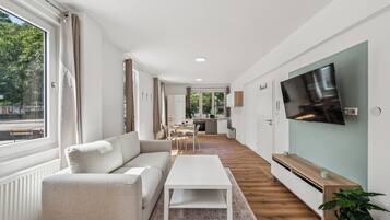 Ein modernes Wohnzimmer mit Sofa, Couchtisch und einem an der Wand montierten Fernseher.