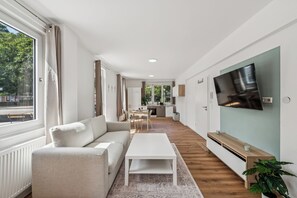 Ein modernes Wohnzimmer mit Sofa, Couchtisch und einem an der Wand montierten Fernseher.