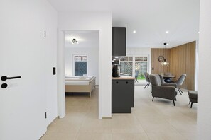 A modern interior with a bed, a dining area with chairs, and a kitchen counter.