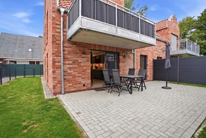 Una casa moderna con facciata in mattoni, un portico coperto con mobili da esterno e una cucina a vista.