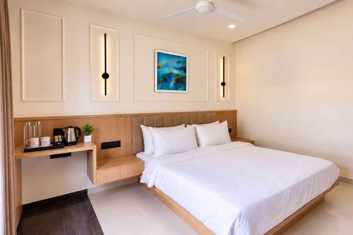 A hotel room with a bed, bedside table, and a painting on the wall.