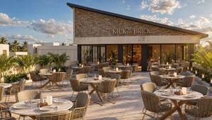 An outdoor dining area with wicker furniture and a stone facade of a building labeled 'KICK IN THE BRICK'.