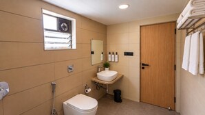 Un baño moderno con inodoro, lavamanos y ducha. Cuenta con una ventana con persianas, un perchero para toallas y una puerta.