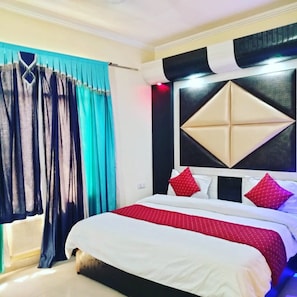 Una habitación de hotel con una cama, cortinas y cabecera con diseño geométrico.