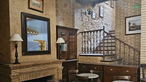 Interior de restaurante con paredes de ladrillo, muebles de madera y una escalera.