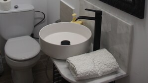 Un baño con inodoro, lavamanos y espejo.