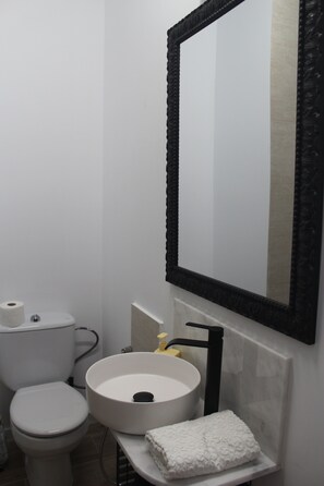 Un bagno con il water, un lavandino e uno specchio.