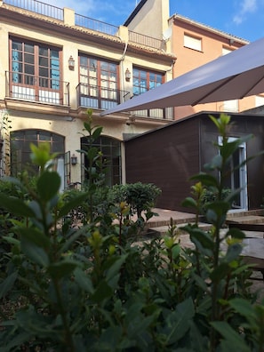 A courtyard with a building featuring large windows and a balcony. - Lotel Casa Noble La Solana (València)