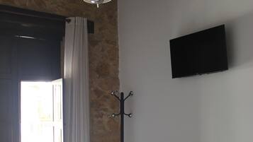 Un dormitorio con cama, candelabro, perchero y televisor en la pared.