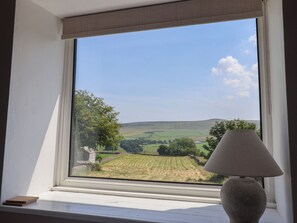 A window with a view of a rural landscape, a lamp, and a small wooden object on the windowsill. - Lyndhurst (Leyburn)