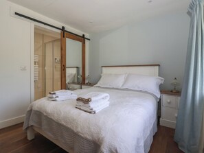 A hotel room with a bed, a nightstand, a mirror, a wardrobe, and a bathroom with a shower. - Lyndhurst (Leyburn)