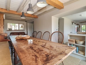 A spacious dining area with a large wooden table, multiple chairs, pendant lighting, and a view of the kitchen. - Lyndhurst (Leyburn)
