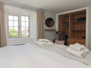 Ein Schlafzimmer mit einem großen Bett, einem Kleiderschrank, einem Spiegel und einem Fenster mit Vorhängen.