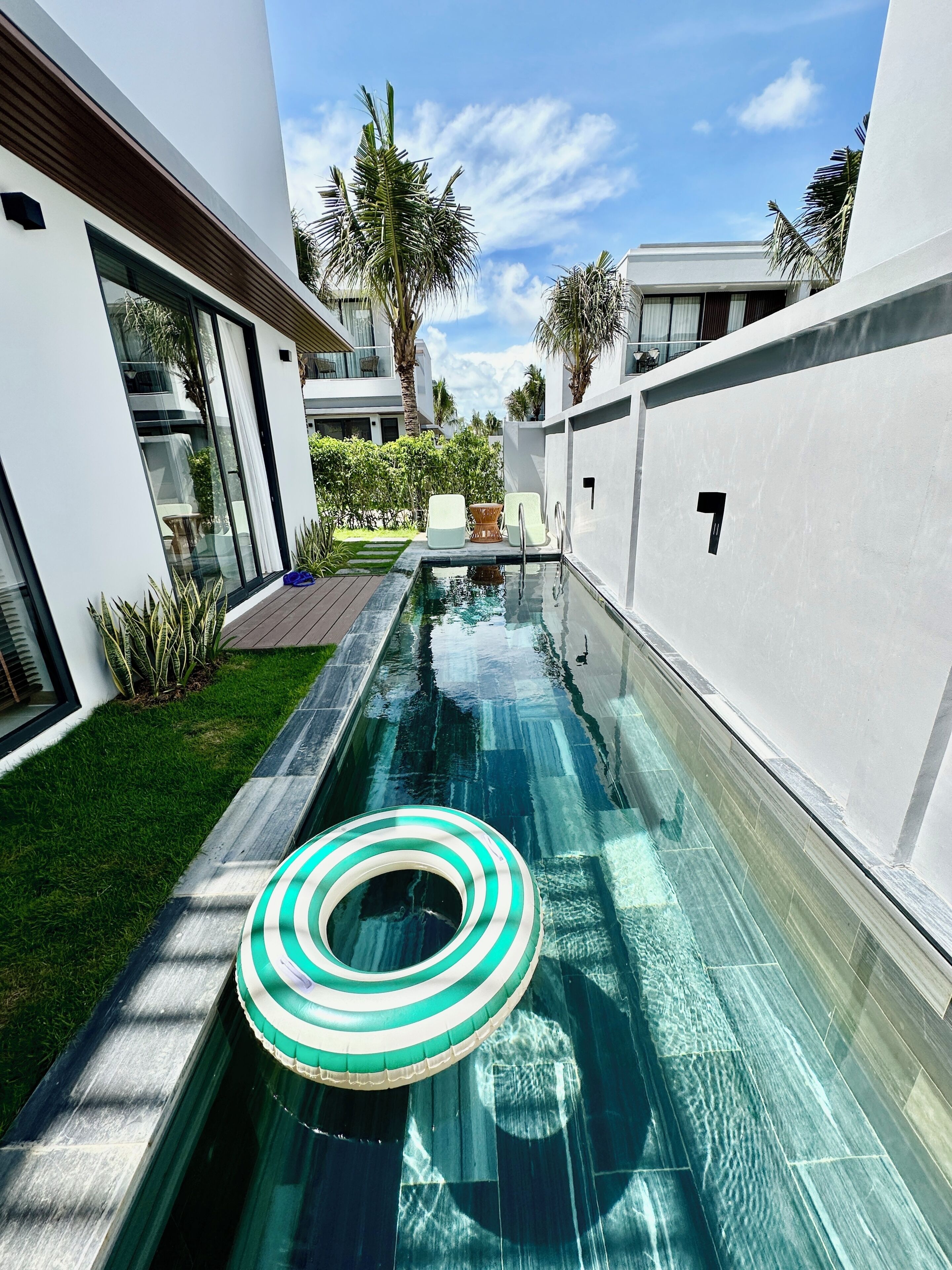 A modern pool area with a clear water surface, surrounded by white walls and a wooden deck.