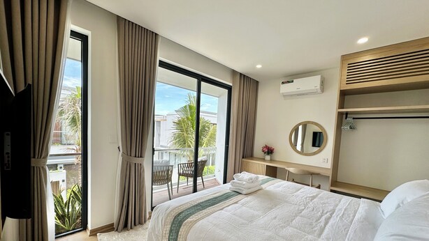 Ein Hotelzimmer mit Bett, Schreibtisch, Spiegel und Blick ins Freie.