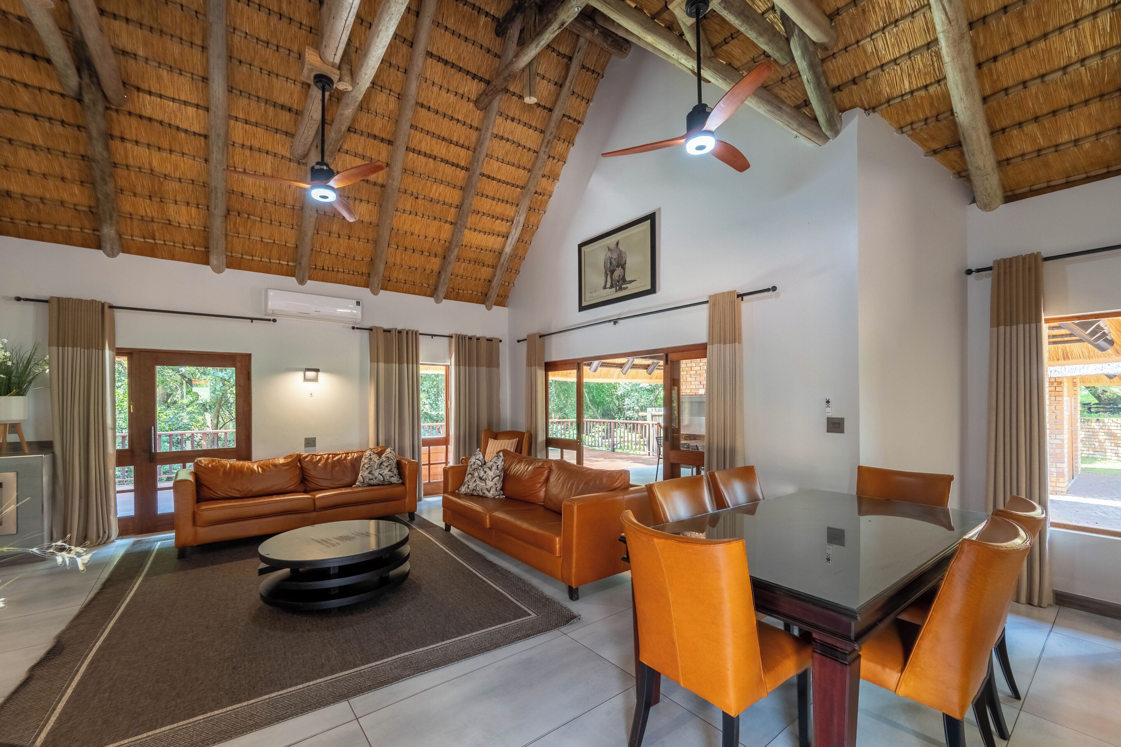 A spacious living area with a high ceiling, a dining table, and comfortable seating.