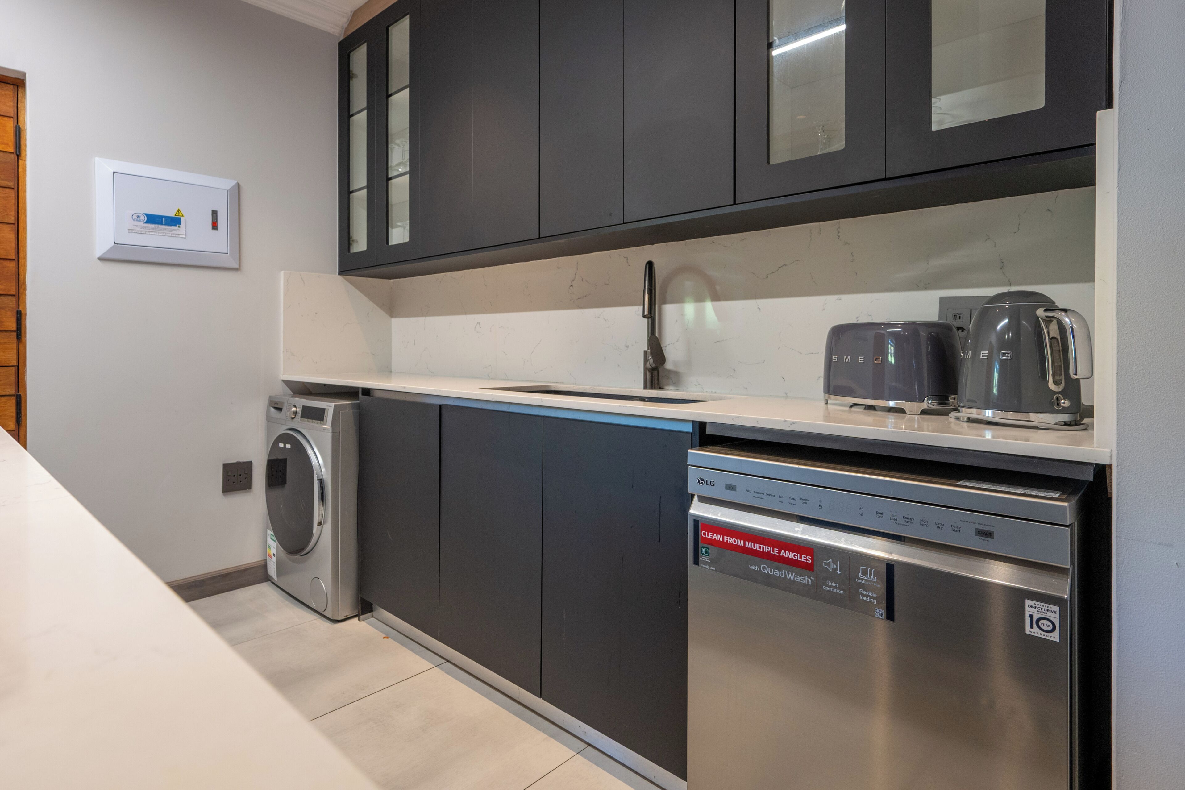 A modern kitchen with a built-in washer, dishwasher, and coffee maker.