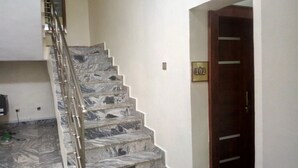 A staircase with a marble finish leading to a door marked with the number 102. - Aden 360 By Intra  (Abuja)
