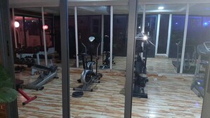 A gym with exercise equipment, a large mirror, and a wooden floor. - Aden 360 By Intra  (Abuja)