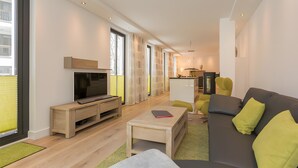Un salon moderne avec un téléviseur à écran plat, un canapé et une table basse.