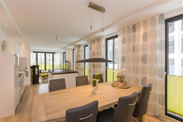 A modern dining area with a wooden table, chairs, and a central light fixture.