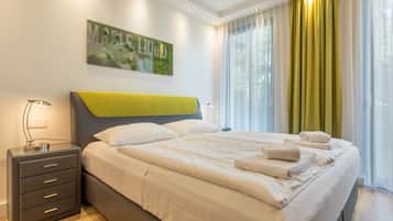 A modern hotel room with a large bed, a bedside table with a lamp, and a painting on the wall.