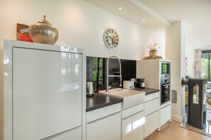 A modern kitchen with a built-in oven, a coffee maker, and a clock on the wall.