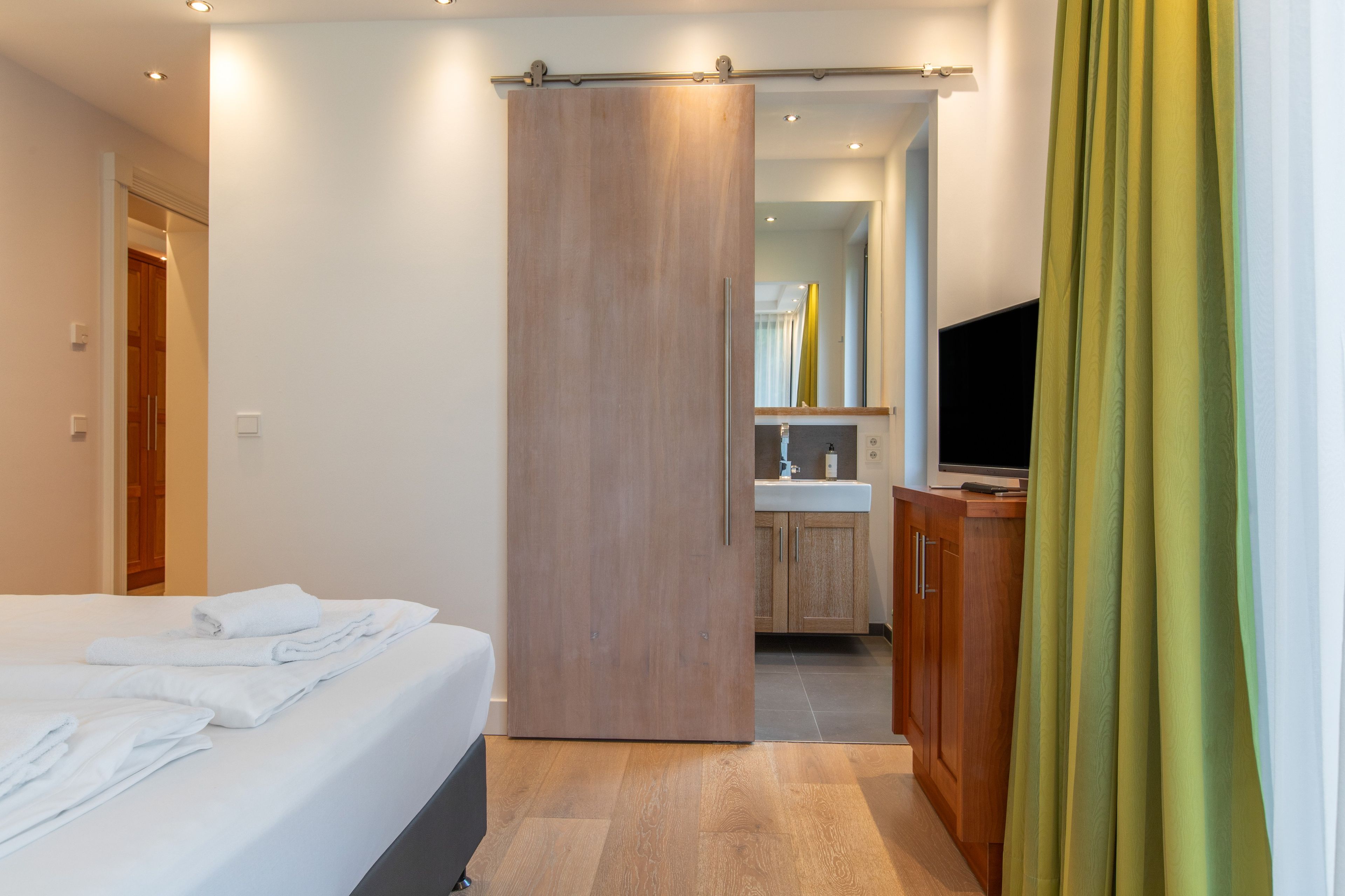 A hotel room with a bed, a bathroom with a mirror, and a television.