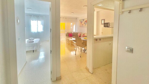 Ein Hotelzimmer mit einem Bett, einem kleinen Tisch und einem Stuhl. Es gibt eine Küchenzeile mit einer Mikrowelle und einem kleinen Kühlschrank. Das Zimmer hat ein Fenster mit Vorhängen.