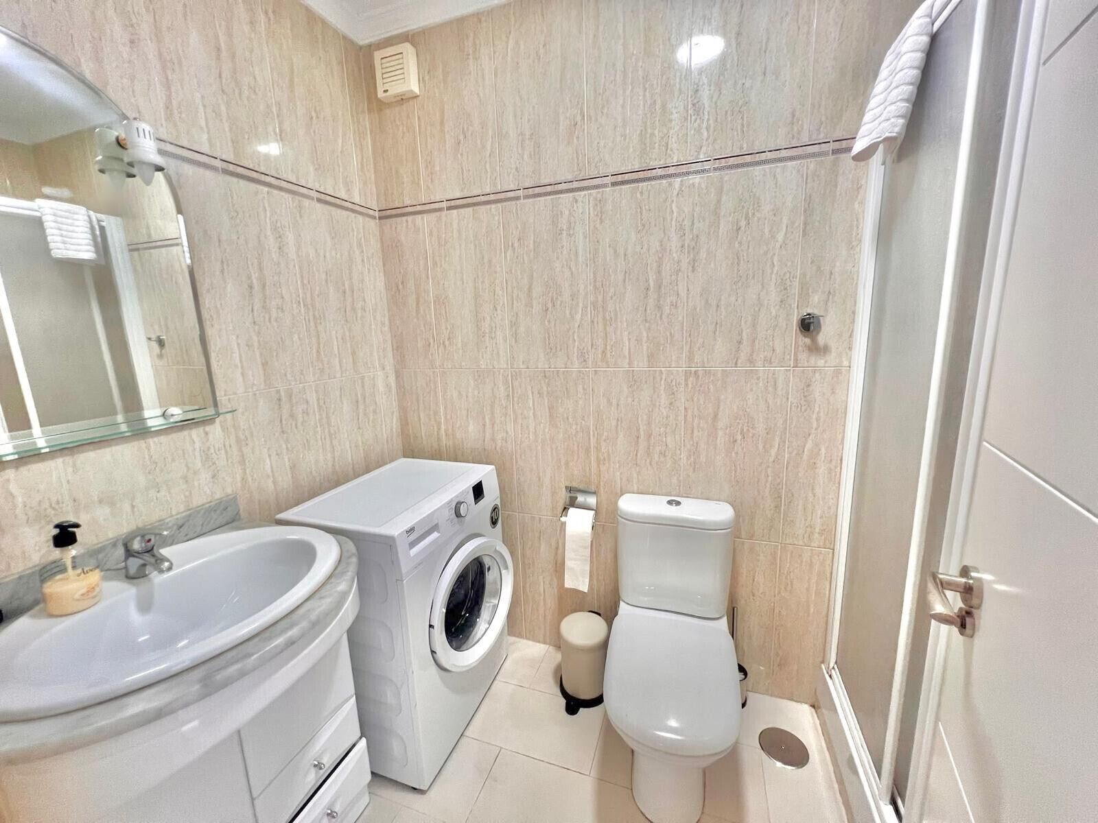 Ein modernes Badezimmer mit Waschbecken, Waschmaschine, Toilette und Spiegel.
