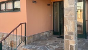 Ein Gebäude mit einer Steintreppe, die zu einer Tür, einem kleinen Fenster und einer Steinsäule führt.