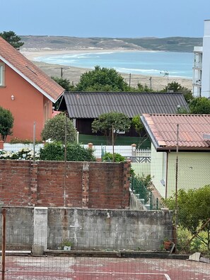 Een woonwijk met uitzicht op de oceaan, een bakstenen muur en een tennisbaan.