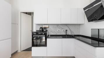 A modern kitchen with white cabinetry, a black countertop, and a built-in oven.