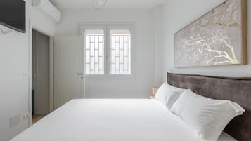 Une chambre à coucher comprenant un lit, une fenêtre, une œuvre d’art accrochée au mur et un appareil de climatisation.