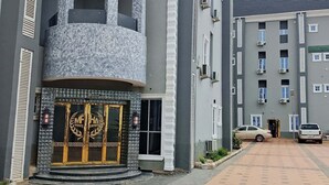 Een meerlaags hotel met een centrale ingang, een decoratieve gevel en een hekwerk.