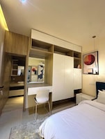 Un dormitorio moderno con escritorio empotrado, cama y armario.
