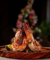 Una tabla de madera con mariscos cocidos, posiblemente camarones, y una porción de aguacate.