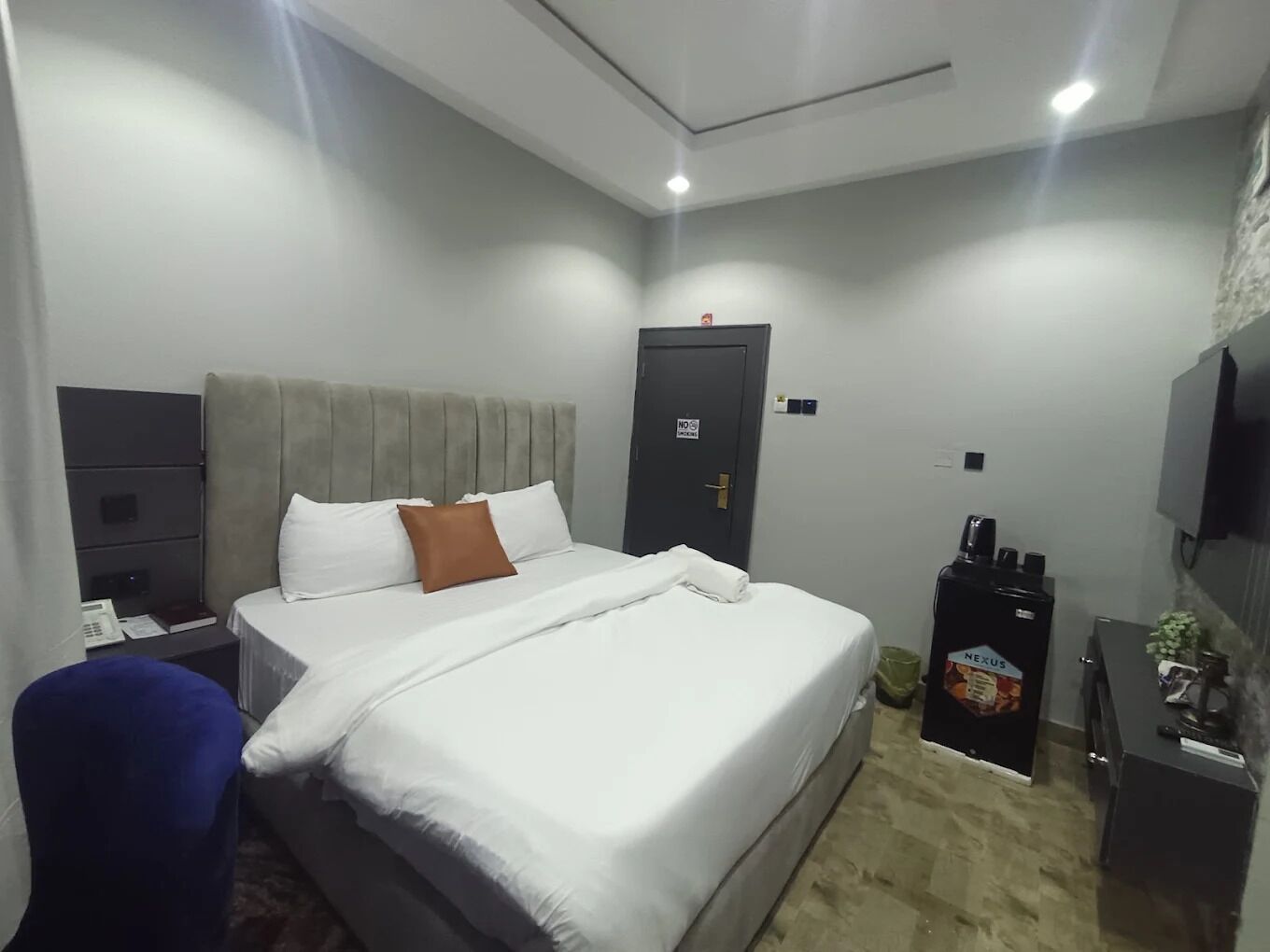 Ein Hotelzimmer mit Bett, Schreibtisch, Stuhl, Kleiderschrank, Fernseher und einer Kaffeemaschine.