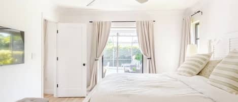 Ein Schlafzimmer mit Bett, Deckenventilator, einer Sitzbank und Blick ins Freie.