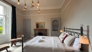 A bedroom with a four-poster bed, a fireplace, a mirror, and a bedside table with a lamp. - Peaceful 6-bedroom house for family and group in charming Berwick-upon-Tweed (Berwick-upon-Tweed)